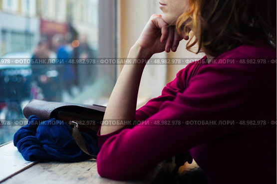 A young woman is sitting by a window and is looking out and day dreaming. Стоковое фото, агентство Ingram Publishing / Фотобанк Лори