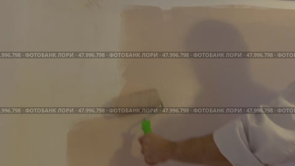 Above view of painter with cap and gloves painting a wall with paint roller, wooden vintage ladder and bucket on background. Стоковое видео, видеограф Ирина Старикова / Фотобанк Лори