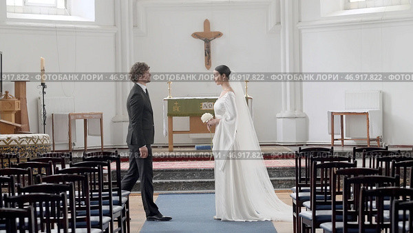 Action.The newlyweds standing in a large temple decorated with crosses and give each other an oath. Стоковое фото, фотограф David Kashakhi / Фотобанк Лори