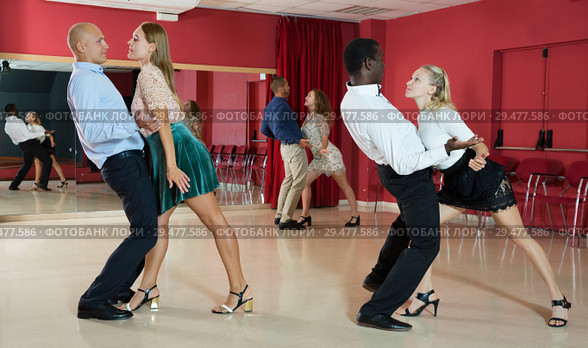 Adult pairs dancing tango movements in modern dance studio. Стоковое фото, фотограф Яков Филимонов / Фотобанк Лори