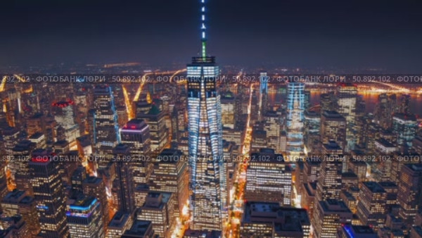 Aerial nighttime view revealing One World Trade Center glowing above Manhattan's luminous urban landscape, highlighting architectural grandeur and metropolitan dynamism. Стоковое AI-видео, аниматор Данил Руденко / Фотобанк Лори