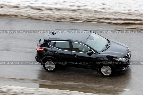 Aerial side view of Nissan Qashqai suv in motion. Black CUV car moving on the slippery winter street. Редакционное фото, фотограф Константин Григорьев / Фотобанк Лори