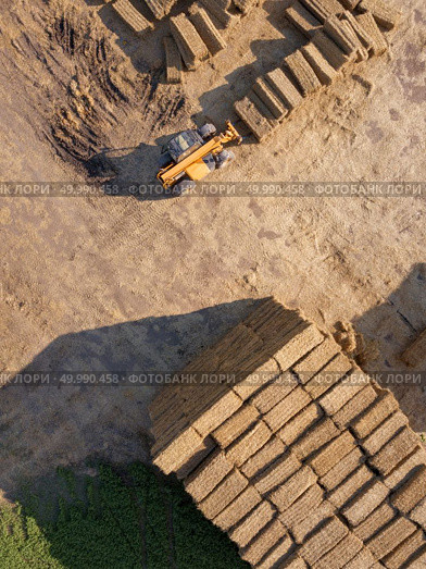 Aerial view from drone agricultural machine collecting bales of hay on a field. Farm industry. Top view. Aerial view of a tractor folding bales of hay in a field on a sunny autumn day. Photo from drone. Top view. Стоковое фото, агентство Ingram Publishing / Фотобанк Лори