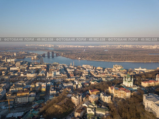 Aerial view from the drone, bird’s eye view to the Vozdvizhenka, Podolsky bridge, St. Andrew’s Church, National Museum of Ukrainian History, Andreevsky descent.. A bird’s eye view, aerial view shooting from drone of the Podol district, oldest historical center of Kiev, the Dnieper River and the left bank of Dnieper in the city of Kiev, Ukraine. Стоковое фото, агентство Ingram Publishing / Фотобанк Лори