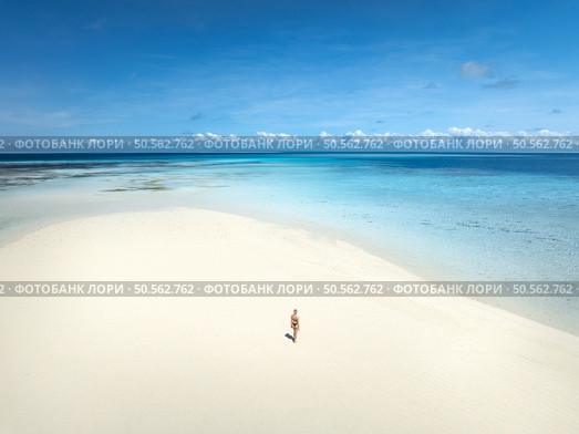 Aerial view of alone young woman on the sandbank in ocean, white sand, blue sea during low tide at sunny summer day in Nakupenda, Zanzibar island. Top view of girl, sand spit, water, sky with clouds. Стоковое фото, агентство Ingram Publishing / Фотобанк Лори