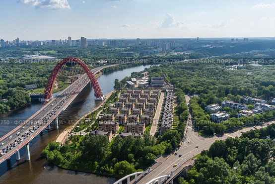Aerial view of the Moscow River with the soaring bridge and lush greenery in the urban landscape during a sunny day in summer. Стоковое фото, фотограф Алексей Климкин / Фотобанк Лори