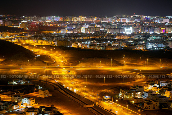 Aerial view of the night city of Muscat - the capital of the Sultanate of Oman. Road junctions and houses illuminated at night (2023 год). Стоковое фото, фотограф Евгений Ткачёв / Фотобанк Лори
