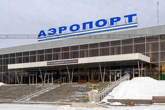Аэропорт Братск, Иркутская область, Россия. Вид на здание аэровокзального комплекса. На крыше здания большая вывеска «АЭРОПОРТ». Над входом в аэровокзал текст «100 лет Гражданской Авиации России». Авиационная транспортная инфраструктура и авиасообщение в Восточной Сибири. (2024 год). Редакционное фото, фотограф Андрей Степанов / Фотобанк Лори