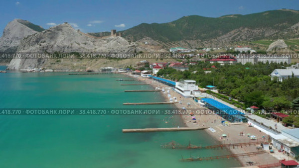 Аэросъемка живописных песчаных пляжей Черного моря с купающимися в голубой воде и отдыхающими людьми, туристами, солнечными зонтиками, лежаками, пирсами и причалами на фоне скал и зеленых холмов природы города Судак Республики Крым (2022 год). Стоковое видео, видеограф Mikhail Leonov / Фотобанк Лори