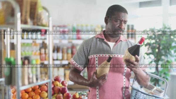 African man hold bottle and choose alcohol wine bottle in store. Стоковое видео, видеограф Яков Филимонов / Фотобанк Лори