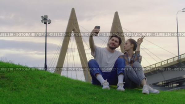 After couples, students relax in the park. A young man, while taking a selfie, accidentally drops his phone. Стоковое видео, видеограф Strunov David / Фотобанк Лори