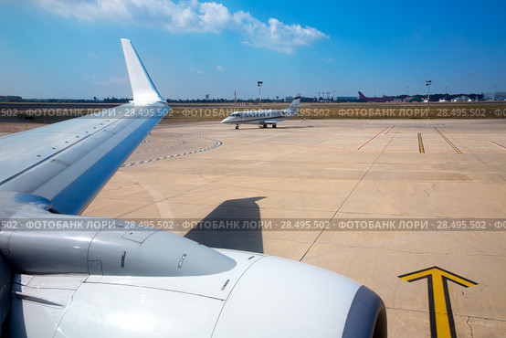 Airplane wing in airport with aircraft background with blue sky. Стоковое фото, фотограф Tono Balaguer / Ingram Publishing / Фотобанк Лори