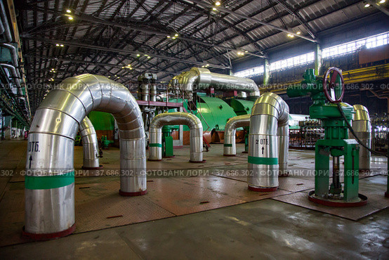 Aksu, Pavlodar region, Kazakhstan - May 29, 2012: Aksu steam power station workshop. Pipes with thermal insulation and shiny metal cover. Green electric machine, steam turbine and generator. Редакционное фото, фотограф Alexey Rezvykh / Фотобанк Лори