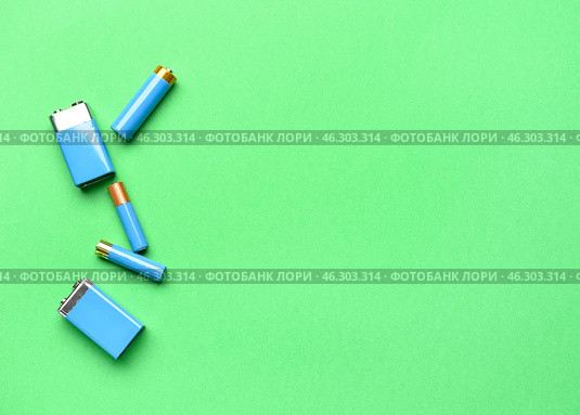 Alkaline batteries on green background, top view. Стоковое фото, фотограф Pixel_shot / Фотобанк Лори