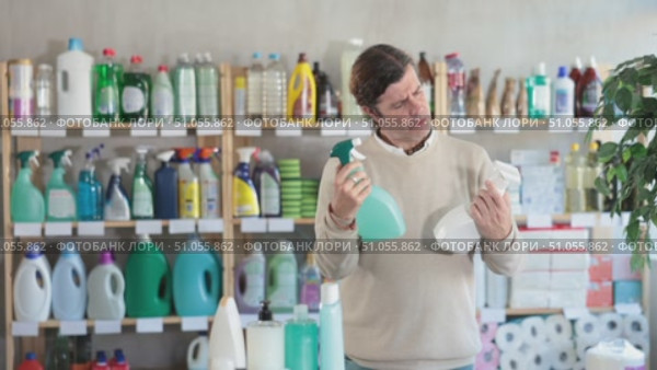 Among shop windows, man buyer leisurely examines goods and chooses glass cleaner spray. Стоковое видео, видеограф Яков Филимонов / Фотобанк Лори