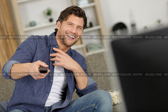 amused man watching tv at home. Стоковое фото, агентство Ingram Publishing / Фотобанк Лори