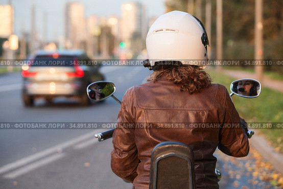 An adult woman motorcyclist on her bike is in the city, rear view. Стоковое фото, фотограф Кекяляйнен Андрей / Фотобанк Лори