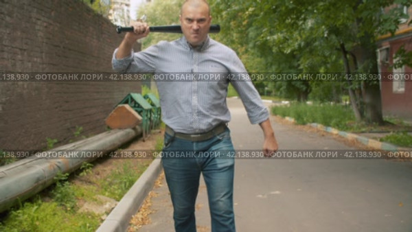 An angry bully with a baseball bat in his hands attacking. Стоковое видео, видеограф Chudakov_Ivan / Фотобанк Лори