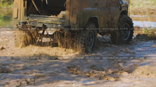 An off-road vehicle is plunging through a muddy puddle, creating a massive splash and showcasing its power and resilience. The car stops, steer driver walks up to it and opens the door. Slow motion. Стоковое видео, видеограф Воловодов Владимир / Фотобанк Лори