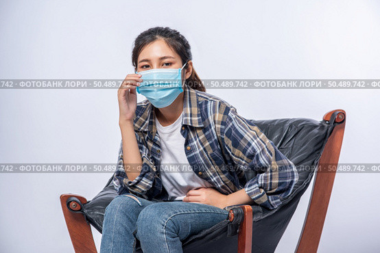 An uncomfortable woman sitting on a chair and wearing a mask. Стоковое фото, агентство Ingram Publishing / Фотобанк Лори