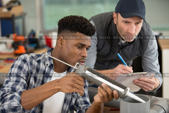 apprentice being advised how to apply caulk. Стоковое фото, агентство Ingram Publishing / Фотобанк Лори