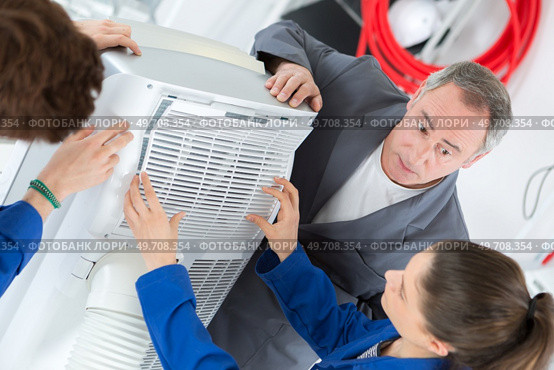 apprentices looking at a portable humidifier unit. Стоковое фото, агентство Ingram Publishing / Фотобанк Лори