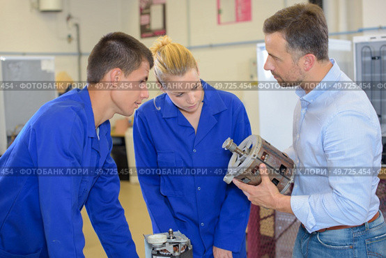 Apprentices looking at electric motor. Стоковое фото, агентство Ingram Publishing / Фотобанк Лори