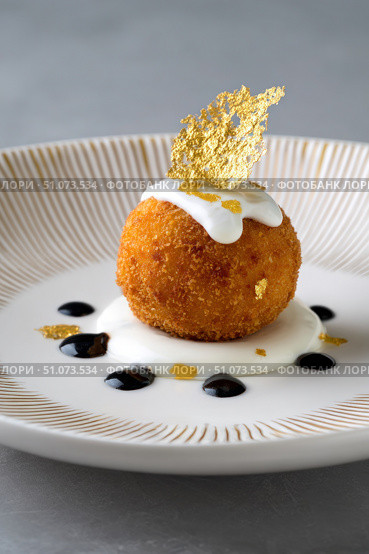 Arancini resting on yogurt cream with balsamic glaze and gold leaf. Стоковое AI-изображение, AI-художник Юрий Поздников / Фотобанк Лори