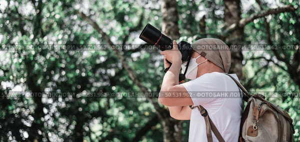 Asian traveler man with backpack taking a photo in the park with copy space. Travel photographer. Vocation and holiday concept. Стоковое фото, агентство Ingram Publishing / Фотобанк Лори