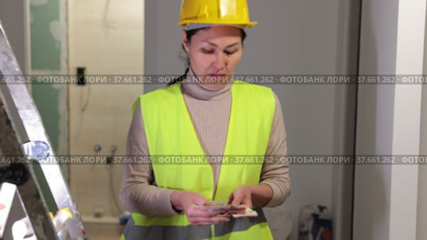 Asian woman repairer standing in apartment holding cash and disappointed by her wage. Стоковое видео, видеограф Яков Филимонов / Фотобанк Лори