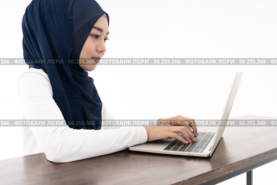 Asian young adult woman wearing hijab using laptop search and doing office work isolated in white background - office, business, finance and work station concept. Стоковое фото, агентство Ingram Publishing / Фотобанк Лори