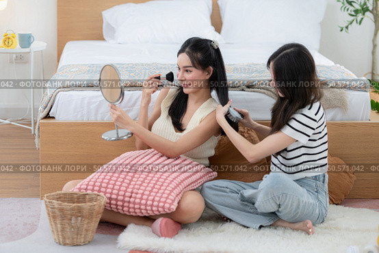 Asian young women conducting their weekly holiday routines from getting up, putting on cosmetics and relaxing. Стоковое фото, агентство Ingram Publishing / Фотобанк Лори