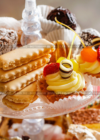 Assorted cakes, cookies and fruits on glass cake stand. Party dessert. Стоковое фото, агентство BE&W Photo / Фотобанк Лори