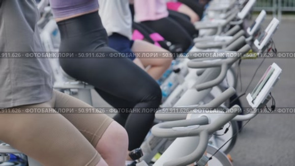 Athletes pedaling on exercise bikes during sports day. Стоковое видео, видеограф Mikhail Davidovich / Фотобанк Лори
