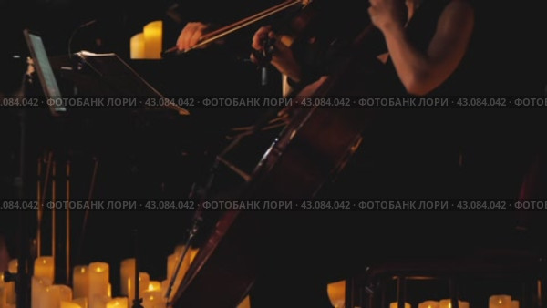 Atmospheric video of a musician playing the cello surrounded by numerous candles. The scene creates a serene and calm atmosphere reflecting the harmony and melody of the music. Стоковое видео, видеограф Воловодов Владимир / Фотобанк Лори