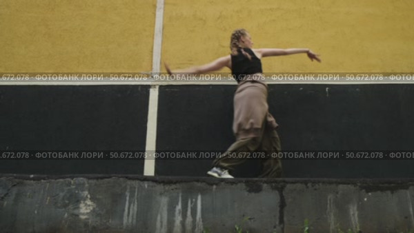 Attractive gen z young woman dancing contemporary dance against urban wall. Стоковое видео, видеограф Маргарита Кирьякова / Фотобанк Лори