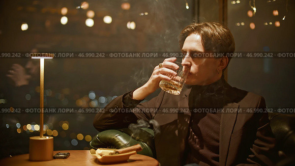 Attractive young man smokes cigar cinematically. Стоковое фото, фотограф David Kashakhi / Фотобанк Лори