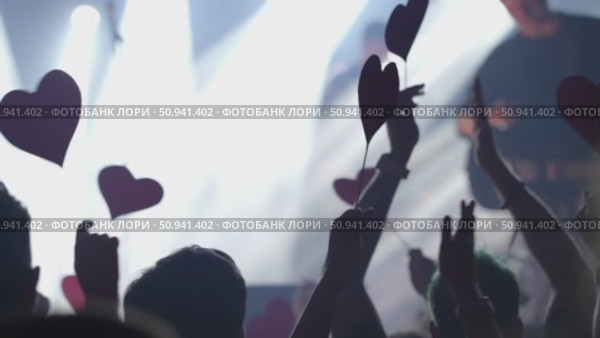 Audience at concert holding heart-shaped signs with vibrant lights creating an energetic atmosphere. Стоковое видео, видеограф Данил Руденко / Фотобанк Лори