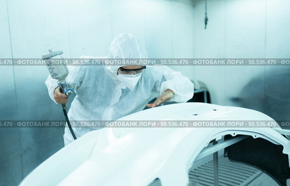 Auto mechanic in car spray room Inspecting the paint sprayed into the front bumper of the car that the pigment is complete, beautiful, harmonious with the original color of the car. Стоковое фото, агентство Ingram Publishing / Фотобанк Лори