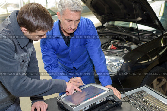 auto mechanic teacher and trainee performing tests at mechanic school. Стоковое фото, агентство Ingram Publishing / Фотобанк Лори