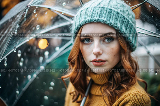 Autumn portrait in the rain. Close-up of a young red-haired woman with expressive green eyes in a knitted hat under an umbrella. Стоковое AI-изображение, AI-художник Photojuli / Фотобанк Лори