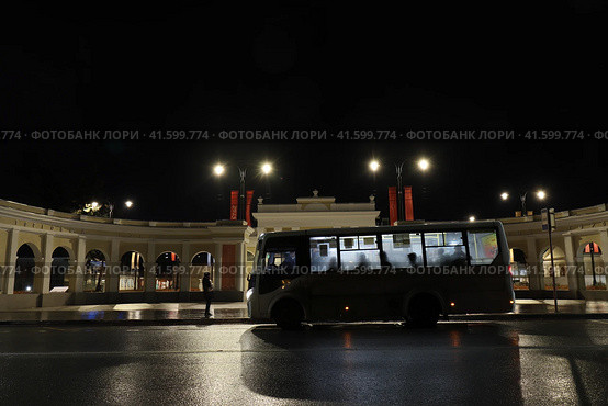 Автобус c пассажирами на остановке общественного транспорта у арки при въезде в торговый городок города Рязани. Ночная фотография. 30 октября 2023 г. Стоковое фото, фотограф Михаил Батурицкий / Фотобанк Лори