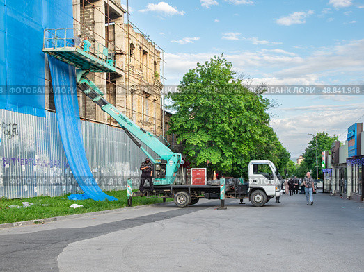 Автогидроподъёмник Isuzu Elf. Рабочие драпируют здание. Редакционное фото, фотограф Лариса Веселова / Фотобанк Лори