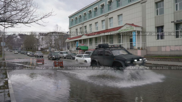 Автомашины проезжают по луже на улице города (2018 год). Редакционное видео, видеограф А. А. Пирагис / Фотобанк Лори