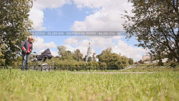 Бабушка толкает коляску внука в парке. Стоковое видео, видеограф Mikhail Davidovich / Фотобанк Лори