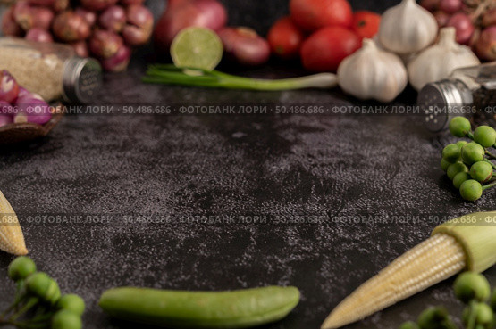 Baby corn, green peas, eggplant, garlic, tomato, lime, scallion and red onion placed on a black cement floor. Стоковое фото, агентство Ingram Publishing / Фотобанк Лори