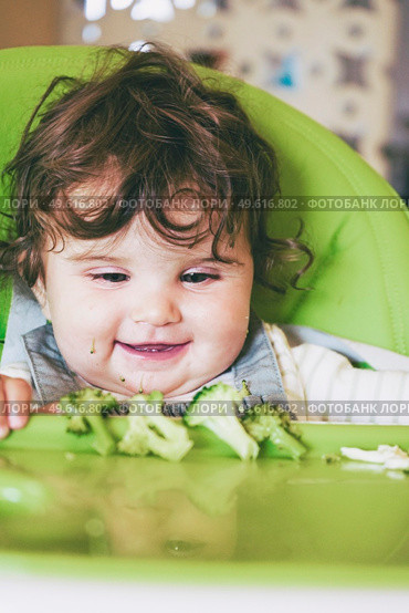 Baby eating food in her green highchair. Стоковое фото, агентство Ingram Publishing / Фотобанк Лори
