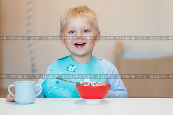 Baby food. Eating. Feeding the baby. A cute kid eats on his own with a spoon. Healthy eating. Family and children. Стоковое фото, фотограф Photojuli / Фотобанк Лори