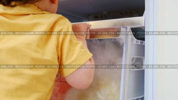 Baby takes a risk and opens the freezer door to grab some ice cream. Always make sure to close the fridge door properly to avoid any accidents Kid aged about two years (one year ten months) Стоковое видео, видеограф Андрей Журавлев / Фотобанк Лори