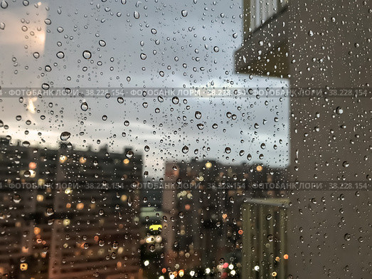 Background drops of water. Raindrop on window panes. Natural pattern of raindrops. Abstract shot of rain drops on glass. Night city and balcony outside window. Selective focus. Space for text or logo. Стоковое фото, фотограф Aleksandr Golubev / Фотобанк Лори